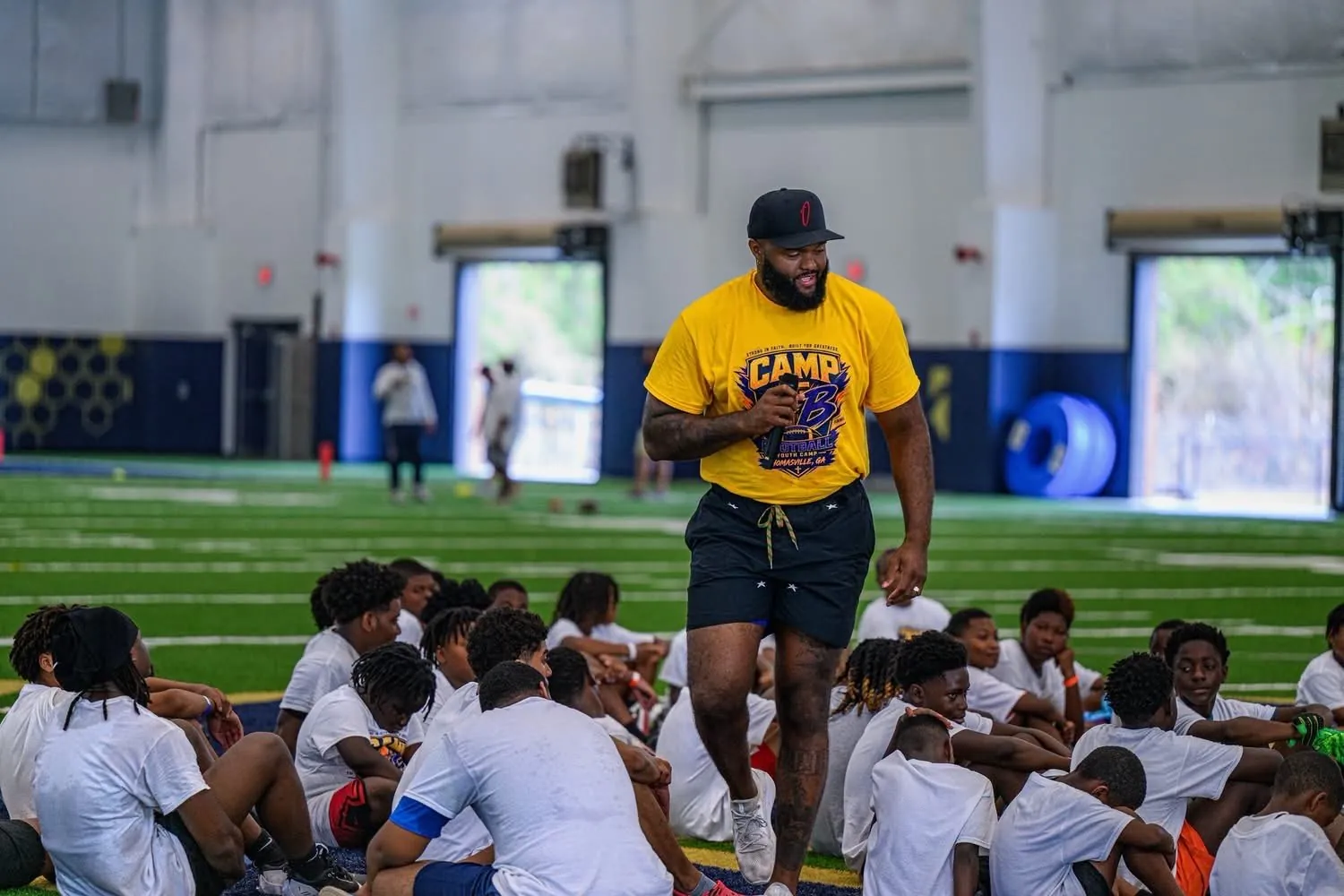 Austin Bryant speaking with seated young athletes at Camp AB